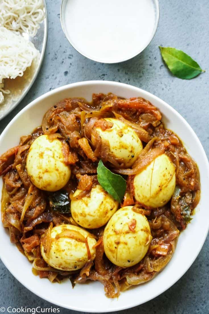 Boiled eggs with tomatoes and onions in a white bowl