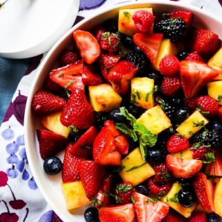 Mixed berries and pineapple in a bowl with a mint dressing on top