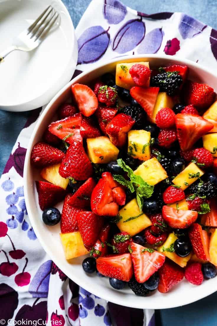 Mixed berries and pineapple in a bowl with a mint dressing on top