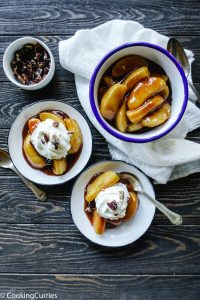 Top shot of Cinnamon Apples in a large white serving bowl and two individual serving size bowls with whipped cream on the cinnamon apples