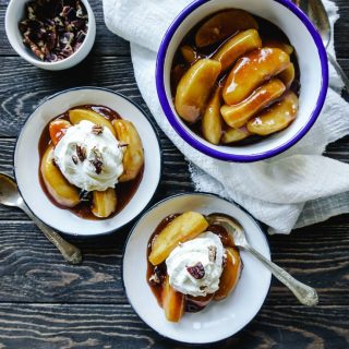 Top shot of Cinnamon Apples in a large white serving bowl and two individual serving size bowls with whipped cream on the cinnamon apples