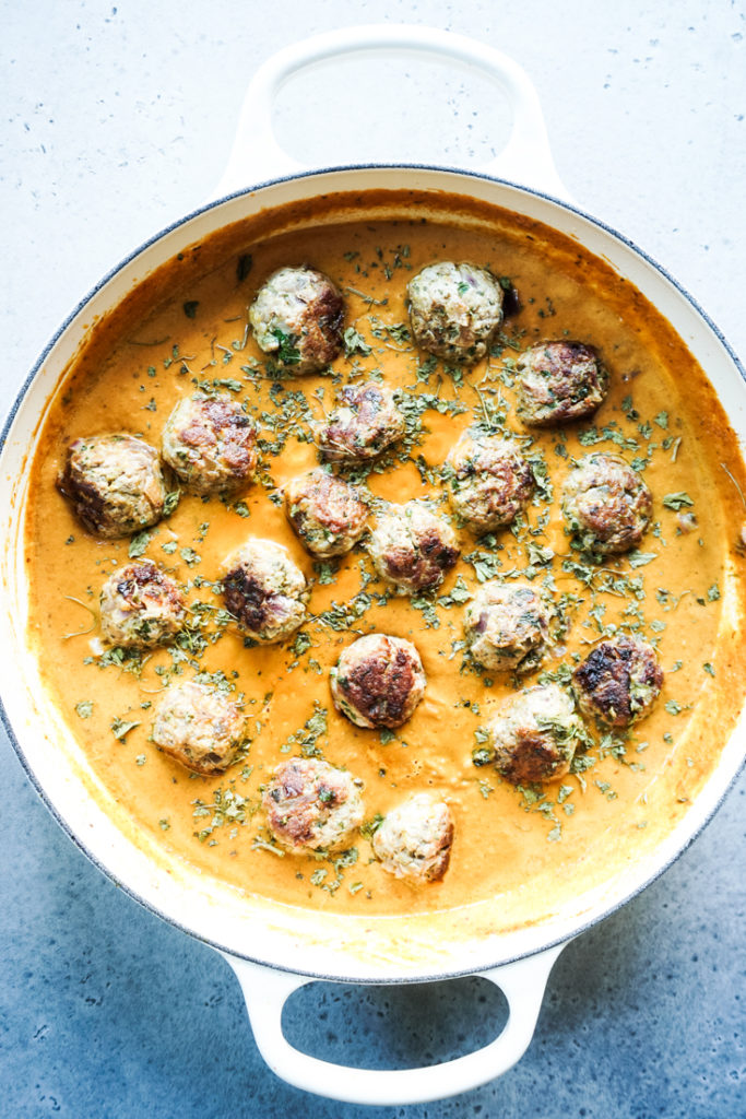 Meatballs in creamy sauce in a white cast iron pan