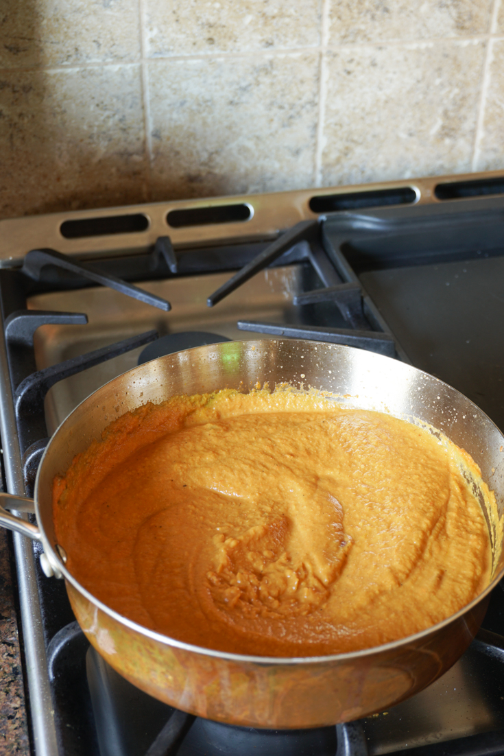 Stainless steel sauce pan on stove with sauce in it