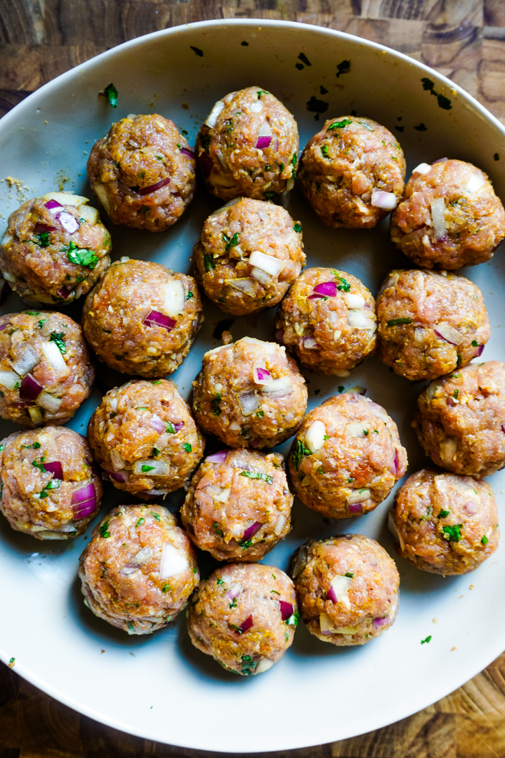 Meatballs ready to be cooked arranged in a white bowl