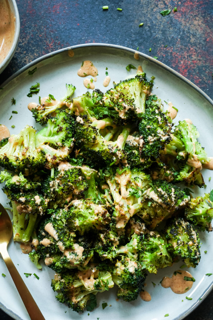 Top shot of Roasted Broccoli on a grey plate and drizzled with tandoori ranch on top