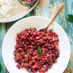 Top shot of a white bowl with carrot and beets saute in it and a brass spoon sticking out