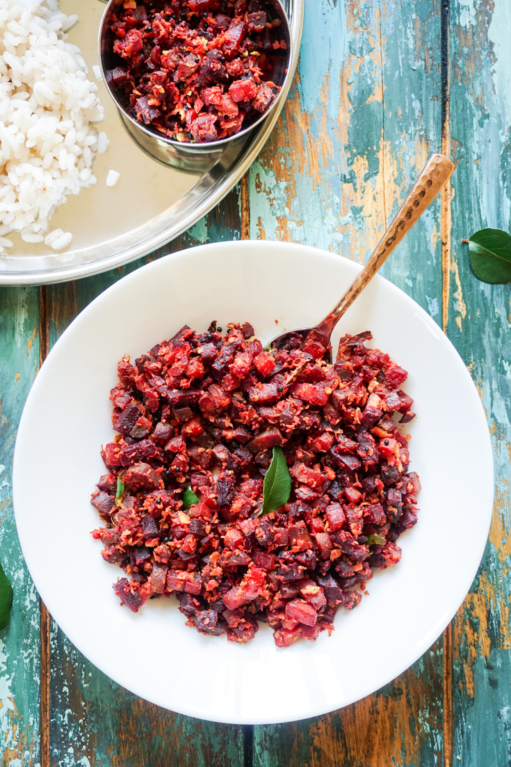 Top shot of a white bowl with carrot and beets saute in it and a brass spoon sticking out