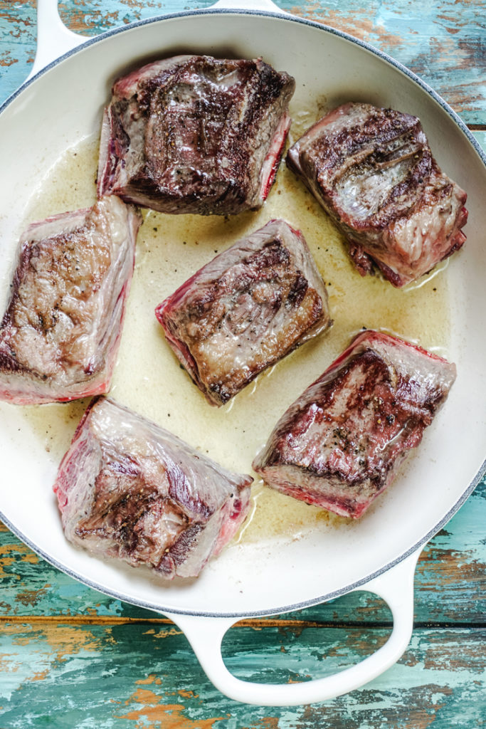Seared short ribs in a white dutch oven