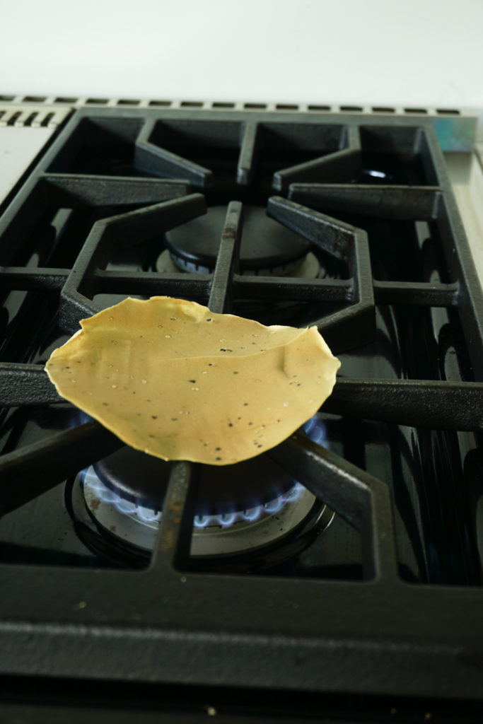 Papad being roasted on open flame of a gas stove