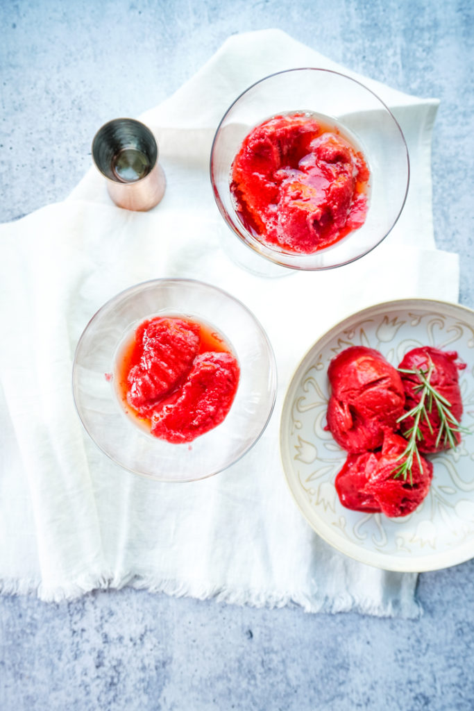 Two champagne coupe glasses with raspberry sorbet in them