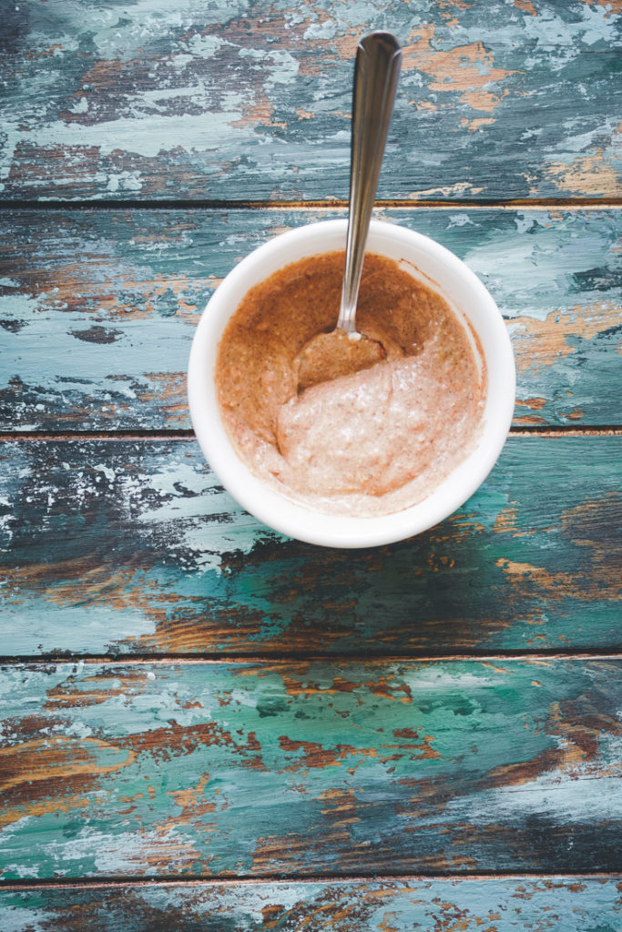 Spices mixed with yogurt in a white bowl with a spoon in it