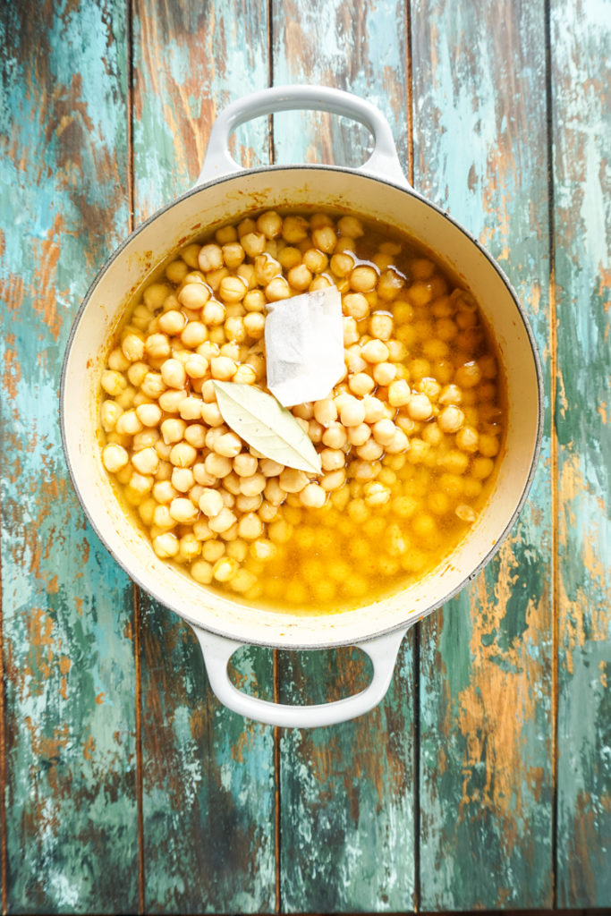 Cooked chickpeas in water topped with a bay leaf and a tea bag