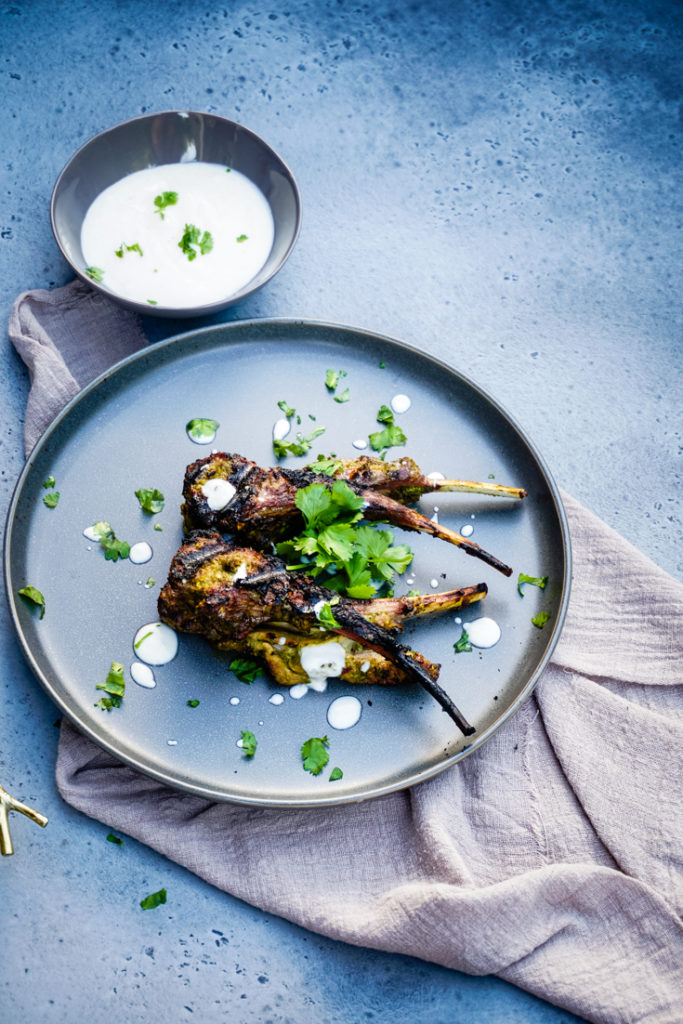 Grilled lamb chops on a gray plate topped with cilantro