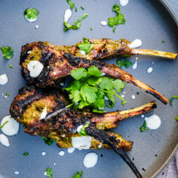 Top shot of grilled lamb chops on a gray plate topped with cilantro