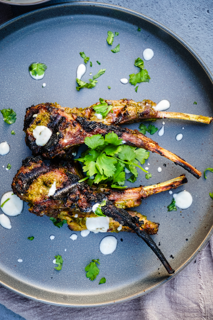 Top shot of grilled lamb chops on a gray plate topped with cilantro