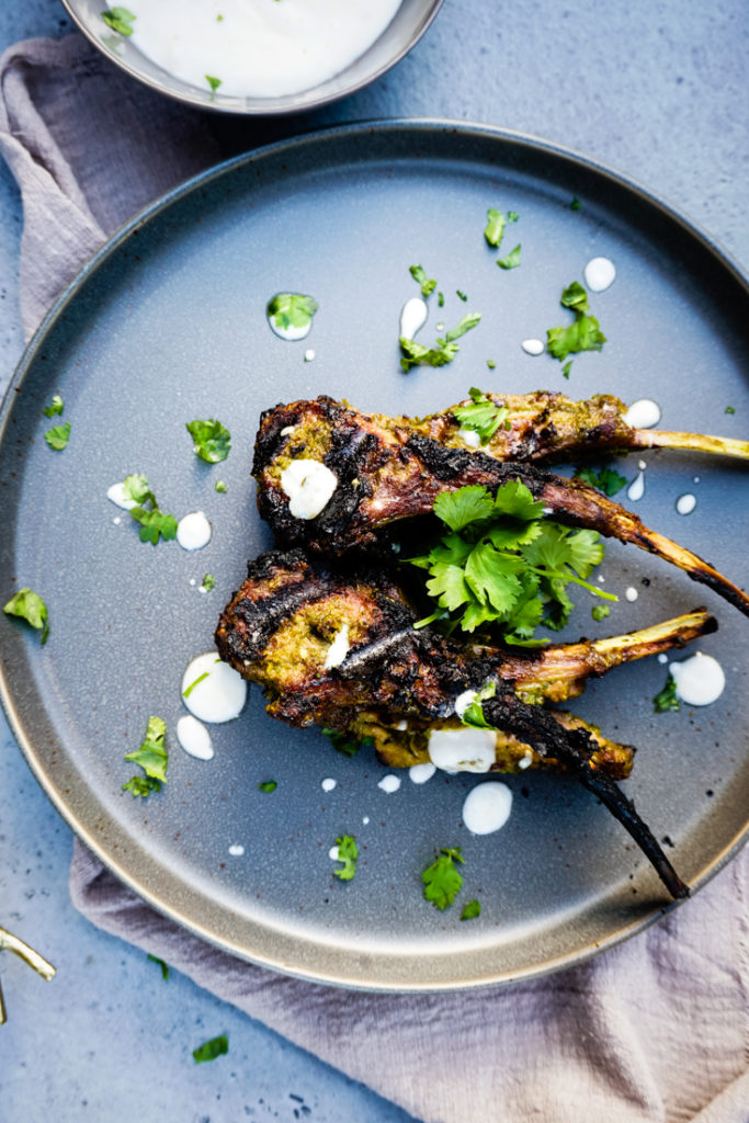 Top shot of grilled lamb chops on a plate topped with cilantro