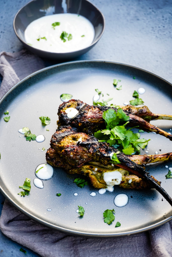 grilled lamb chops on a gray plate topped with cilantro
