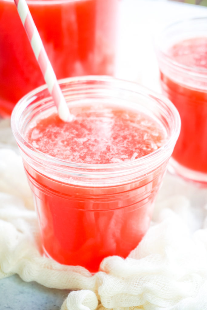 A glass of strawberry lemonade with pink straw in it