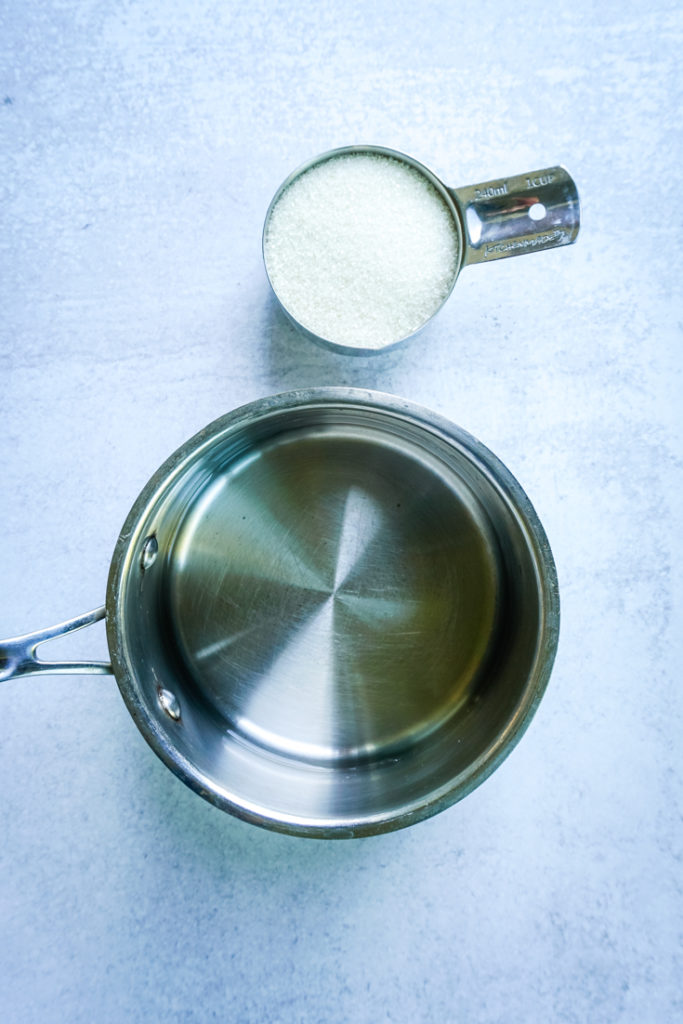 Water in a sauce pan and sugar in a measuring cup to make simple syrup