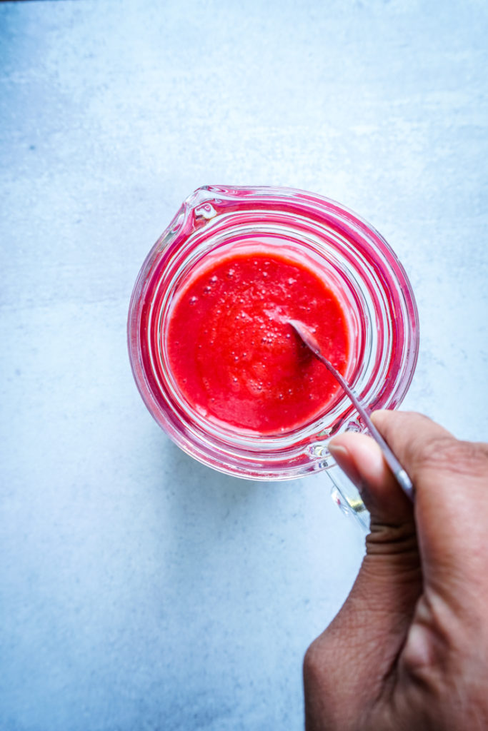 Strawberry syrup and simple syrup being mixed in a pitcher