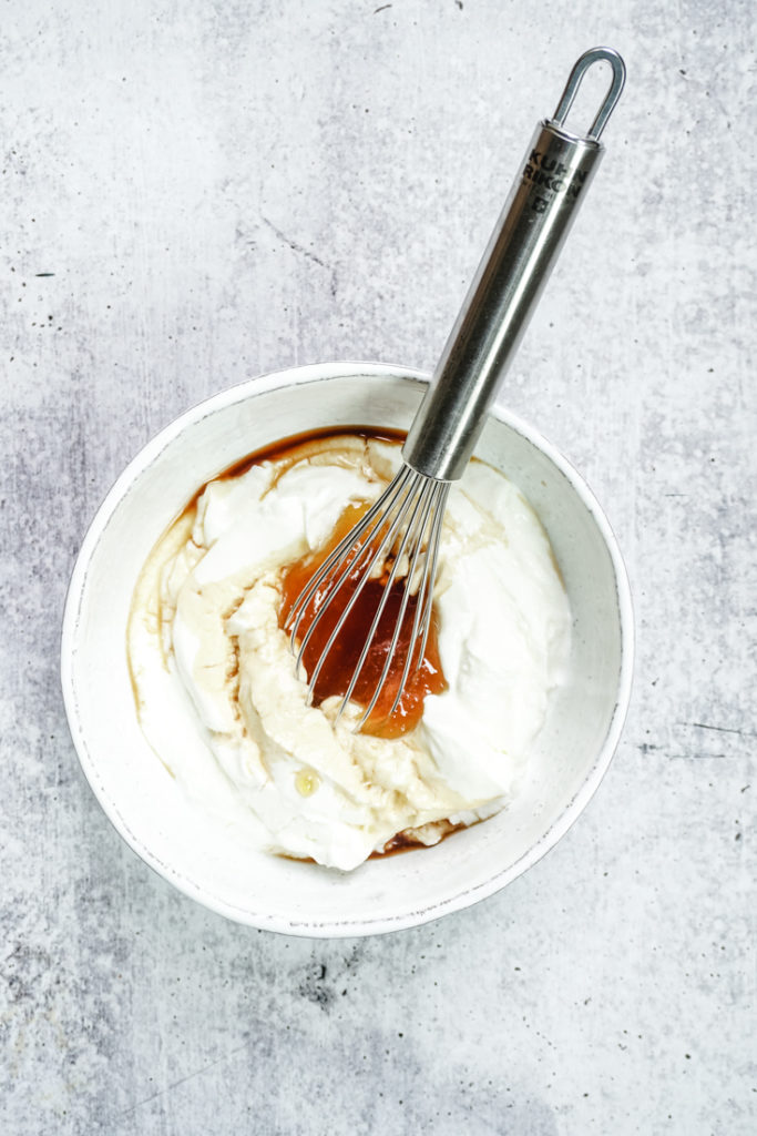 Yogurt with honey and vanilla in a bowl with a whisk in it