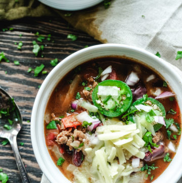 Turkey chili in a white bowl topped with cheese and jalapenos