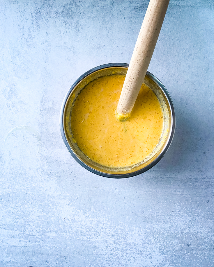 A mixing bowl with wet ingredients mixed in