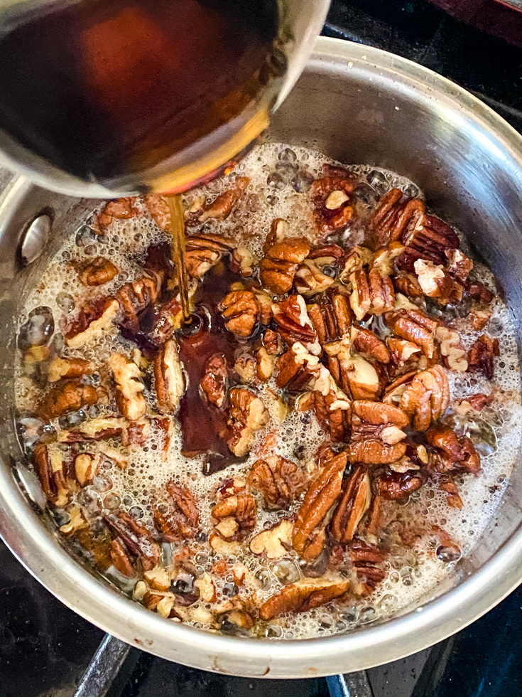 Maple syrup being poured into the melted butter and pecans mix
