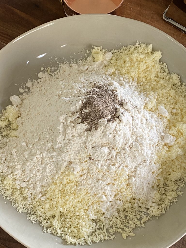 grated khoya, flour and ground cardamom in a white bowl