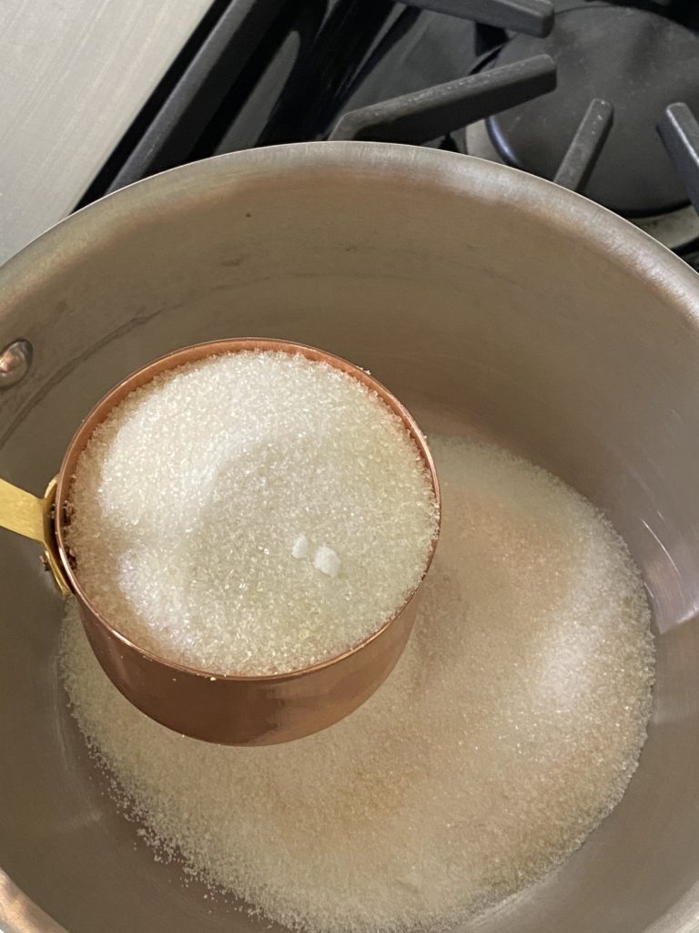 sugar being added to a saucepan