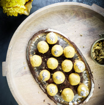 Besan laddoos in a silver platter placed on a wooden board