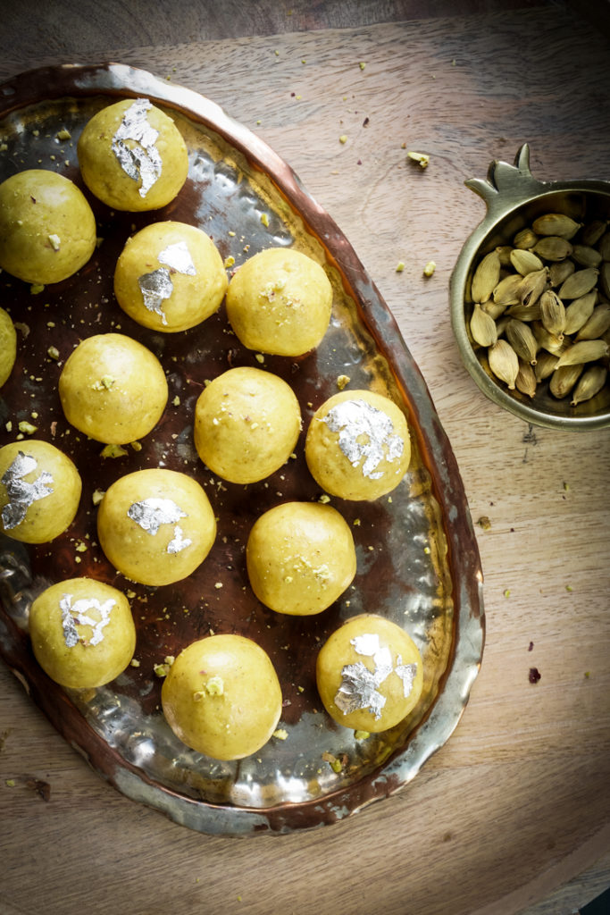 Besan laddoos in a silver platter placed on a wooden board