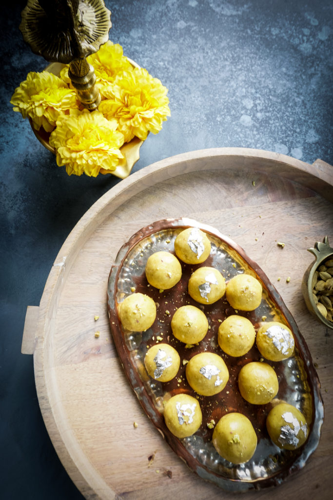 Besan laddoos in a silver platter placed on a wooden board