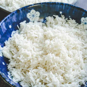 Cooked basmati rice in a blue bowl with more rice on a plate