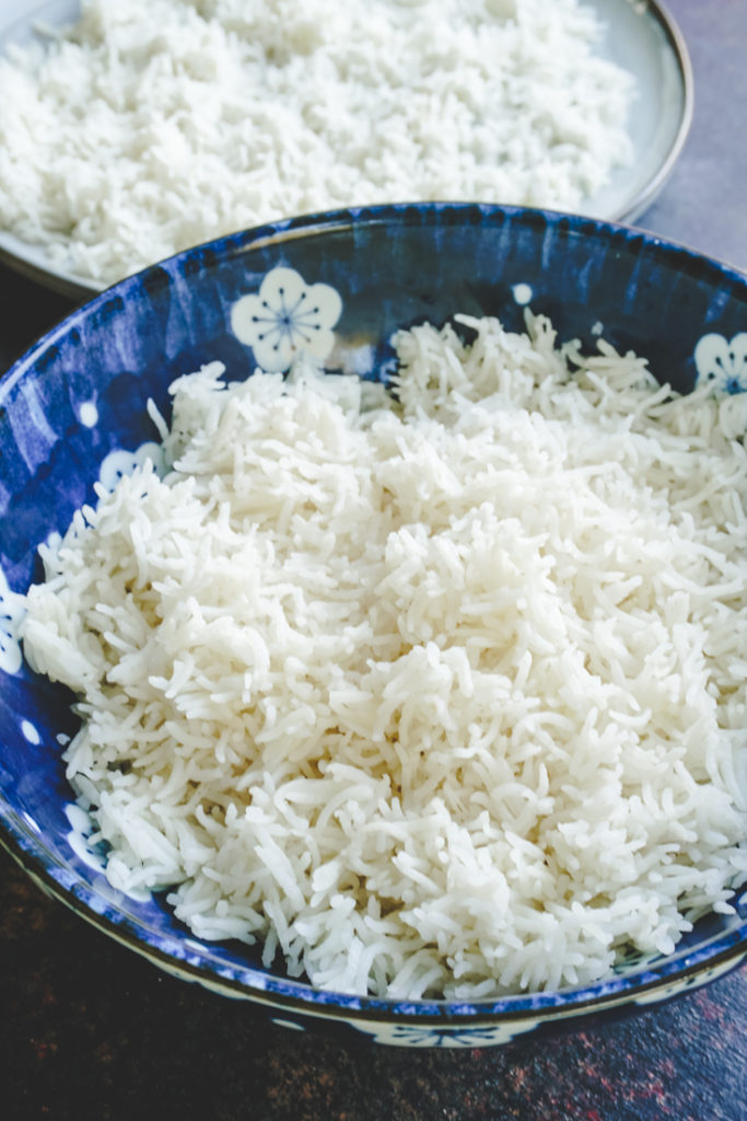 Cooked basmati rice in a blue bowl with more rice on a plate