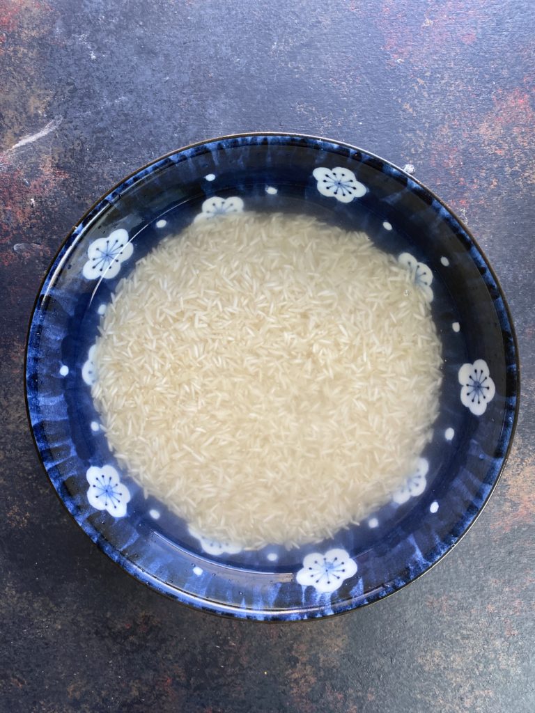 Basmati rice soaking in water in a blue bowl