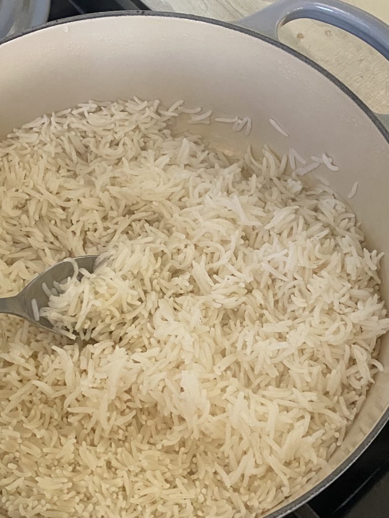 Cooked basmati rice in a dutch oven with a spoon fluffing it