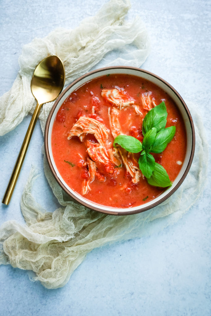 Bowl of tomato chicken soup with basil for garnish