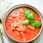 Bowl of tomato chicken soup with basil for garnish