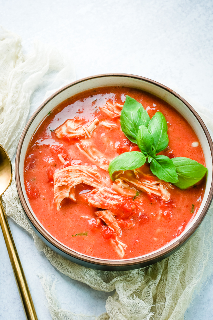 Bowl of tomato chicken soup with basil for garnish