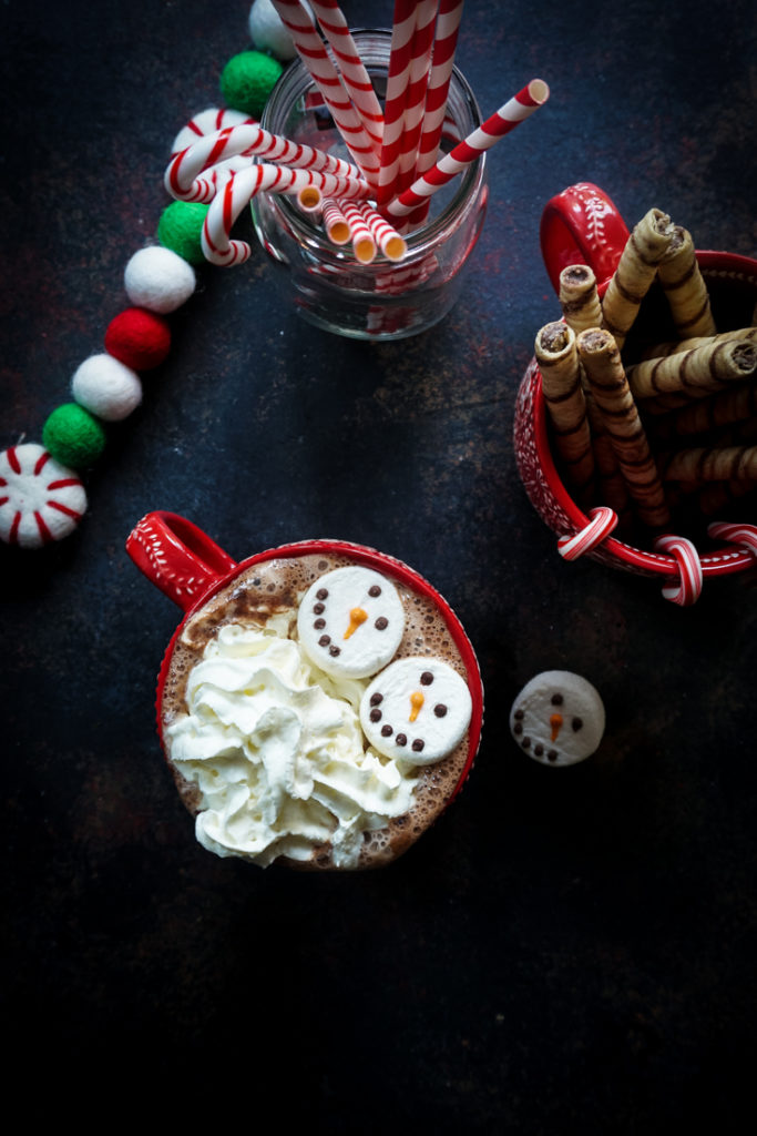 Hot chocolate topped with snowman marshmallows and whipped cream