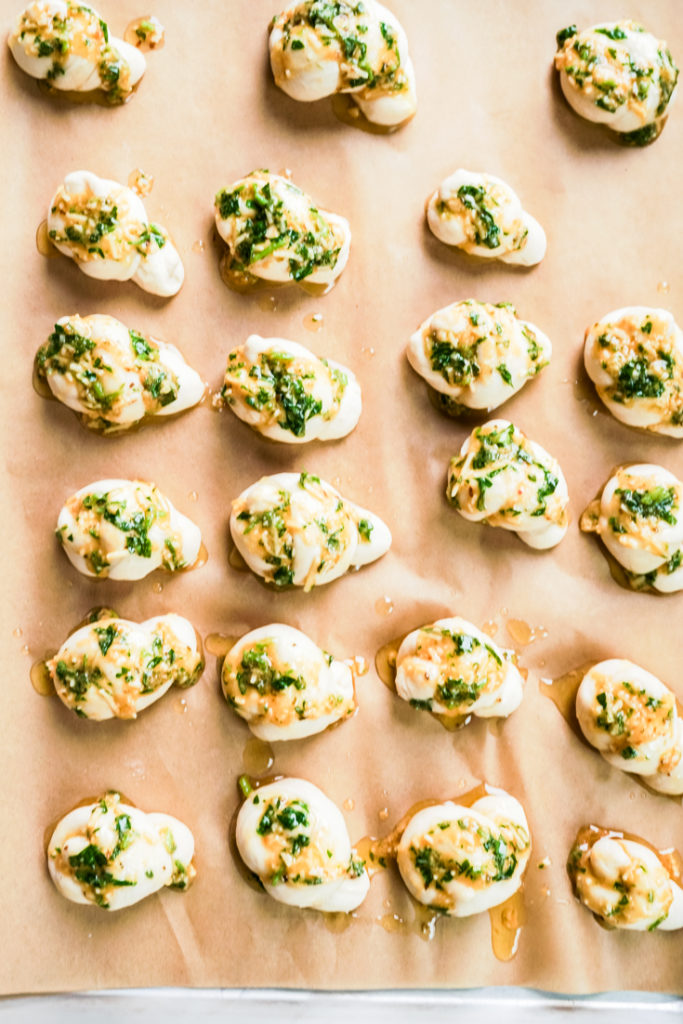 Unbaked Garlic knots lined up in a baking sheet