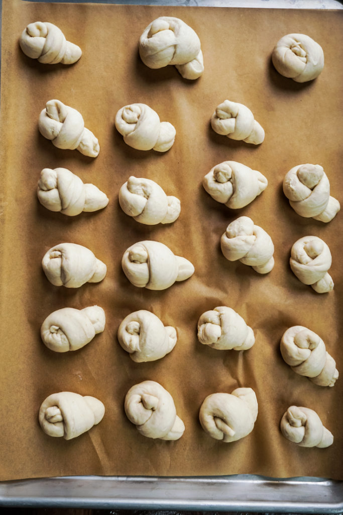 dough knots lined up on a baking sheet