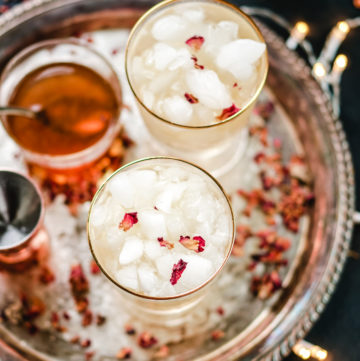 cardamom rose cocktail in two gold rimmed glasses on a silver platter