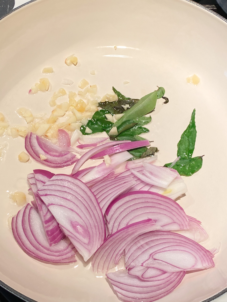 sliced onions and curry leaves in pot