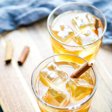 two glasses of maple whiskey sour on a wood board