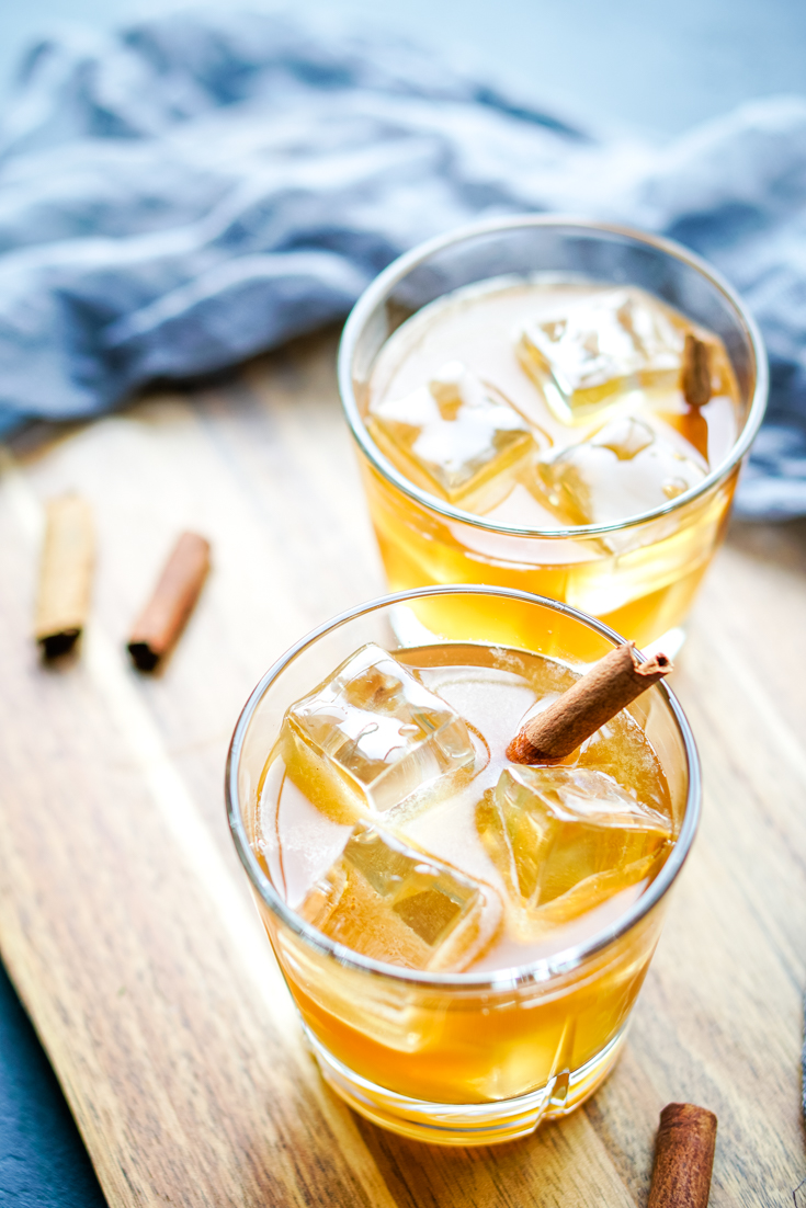 two glasses of maple whiskey sour on a wood board