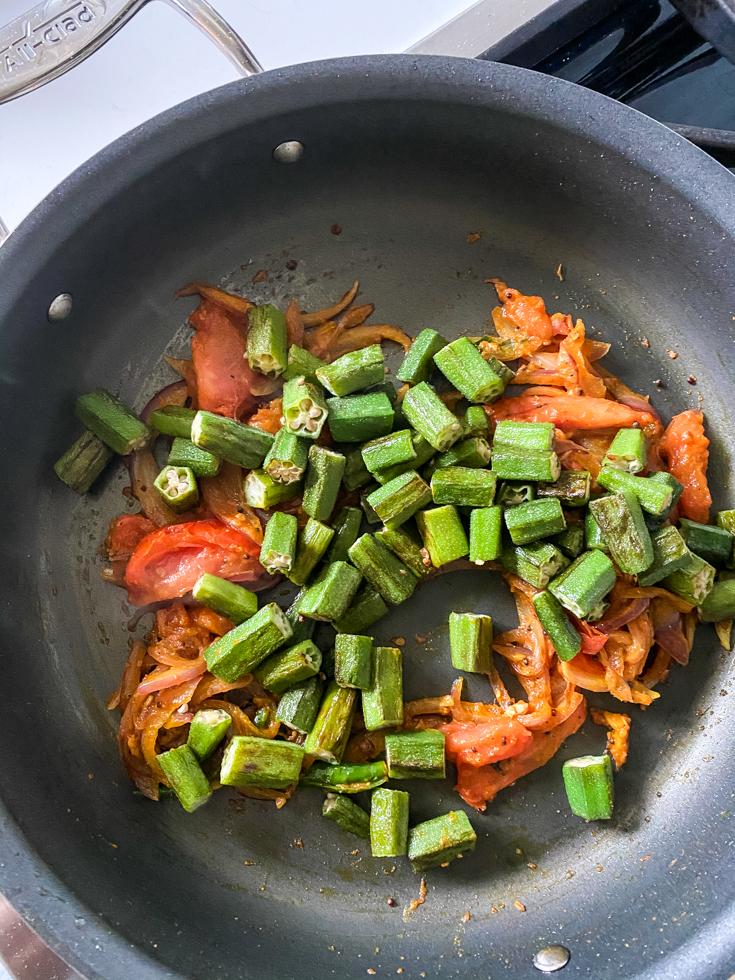 okra with sauteed onions and tomatoes in a saute pan