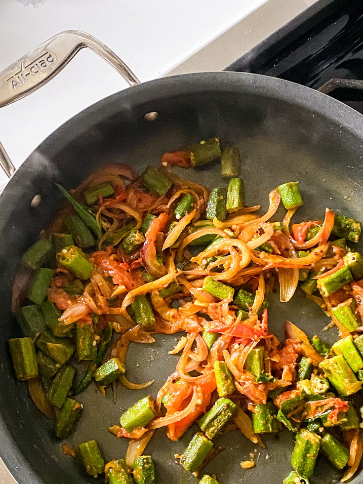 okra with sauteed onions and tomatoes in a saute pan