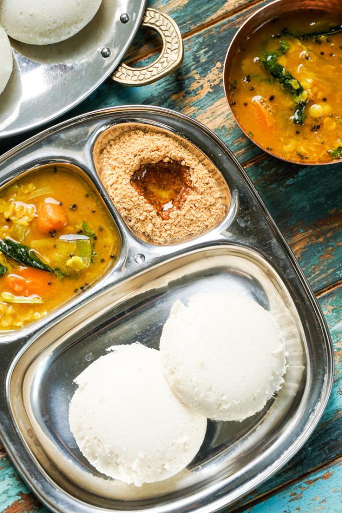 sectioned plate with idlis and sambar in it